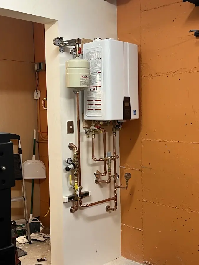 Plumbing technician inspecting water heater connections in Wagoner